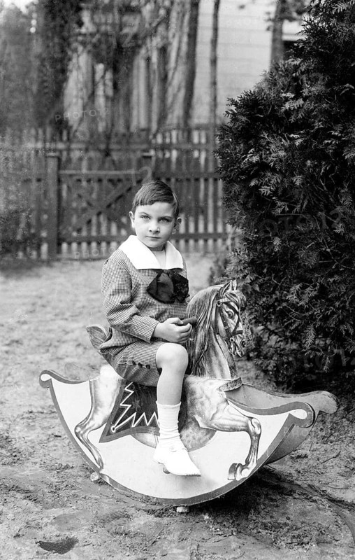Boy on a rocking horse, 1920s, A boy sitting outside on a wooden horse, Historical photo
