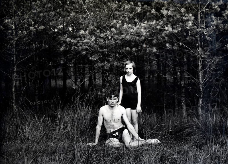 Brother and sister in swimming costumes, 1930s, Two people in swimming costumes in a forest, one sitting, the other standing, looking serious, Historical photo