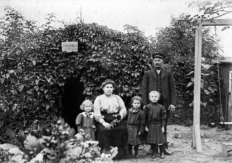 Family photo in the garden, 1930s, Family portrait with parents and three children in front of a pergola in the garden, Historical photo