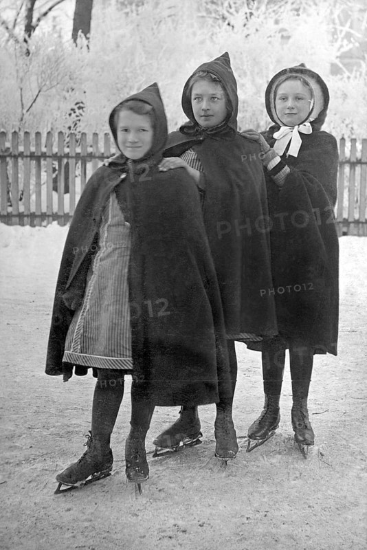 Three girls skating, 1930s, Three girls in hooded coats standing close to each other on an ice rink, Historical photo