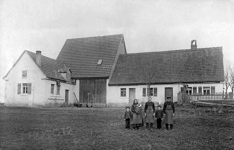 Farmers, family in front of the house, 1920s, Family posing in front of a large rural farmhouse taken on a cloudy day, Historical photo