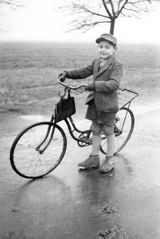 Boy with bicycle, 1920s, Boy standing with bicycle on a wet road in a rural environment, Historical photo