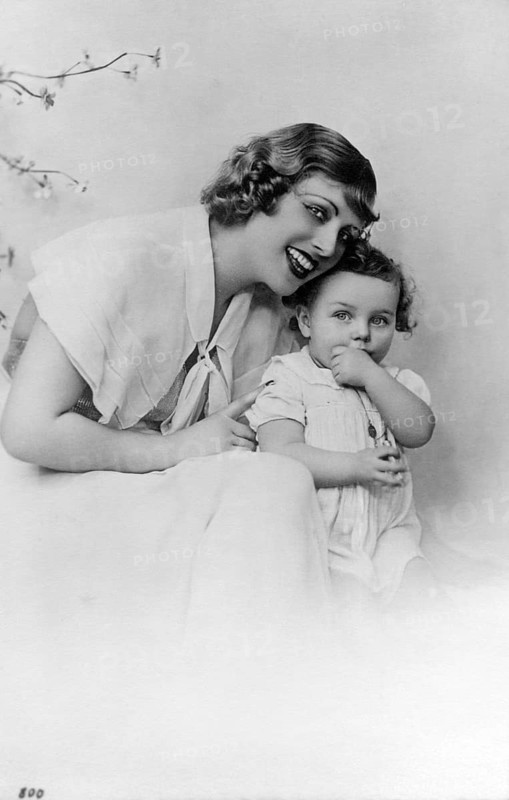 Mother with child, 1930s, Woman and small child sitting next to each other and laughing in a studio portrait, historical photo