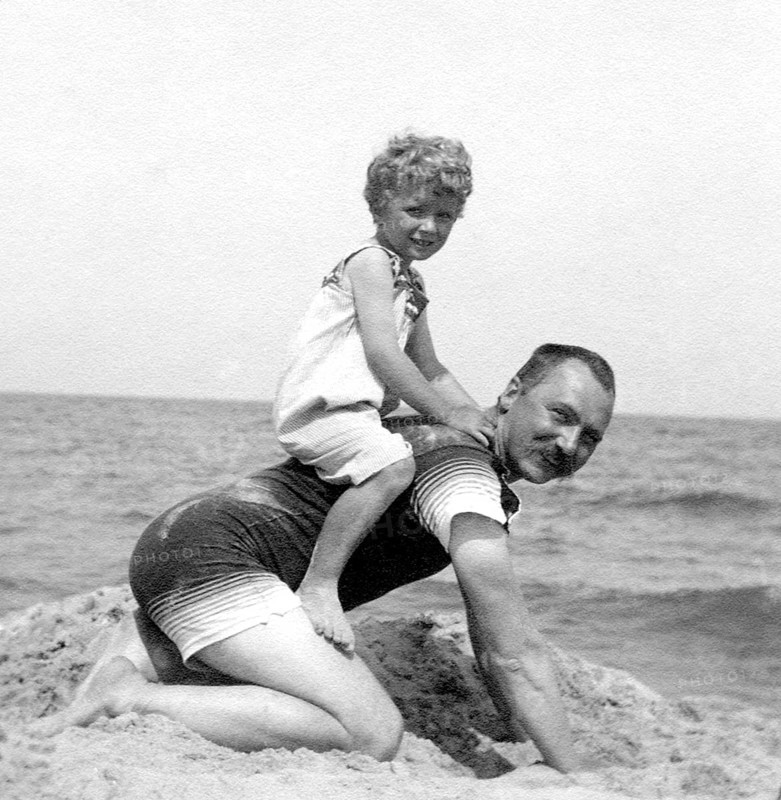 Son sitting on his father on the beach, 1920s, A man on his hands and knees with a happy child on his back on the beach, Historical photo