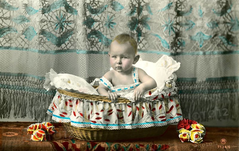 Baby sitting in basket, 1905, A baby sits in a decorative basket draped with colourful fabric, Historical photo