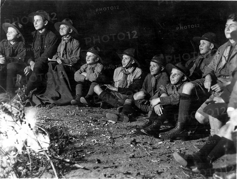 Scout campfire, 1930s, Group of boys in scout suits sitting attentively around a campfire in the dark, historical photo