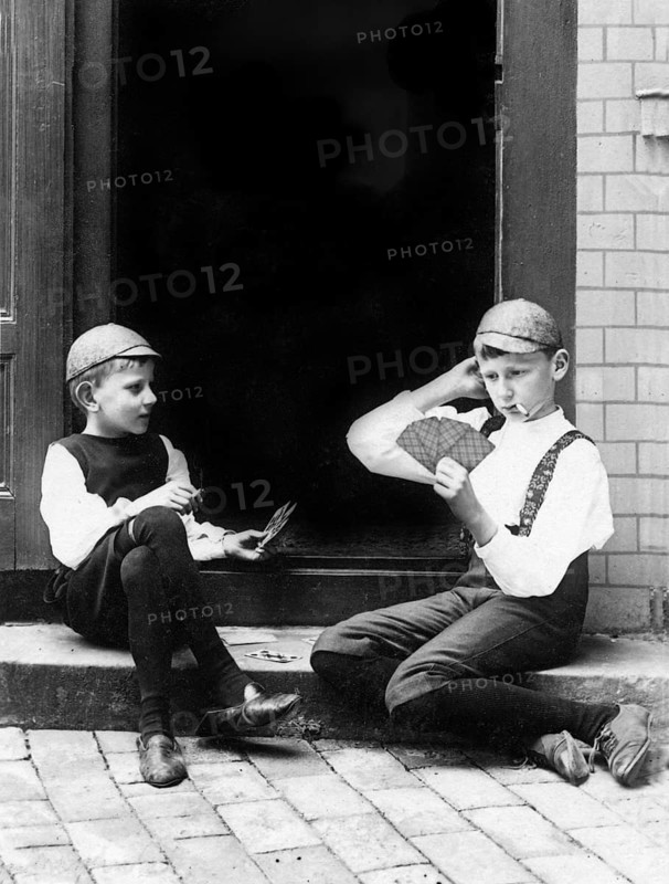 Two children playing cards, 1930s, Two boys in period clothing playing cards on a staircase, Historical photo