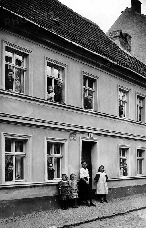 People looking out of windows, 1920, people in a house looking out of windows and standing outside, historical photo