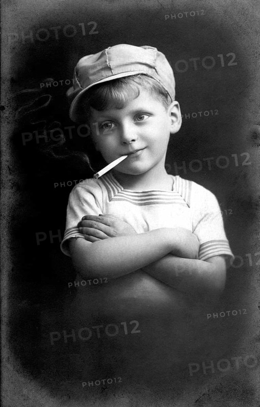 Boy smoking, 1920, Black and white photo of a boy with cap and cigarette in a casual pose, historical photo