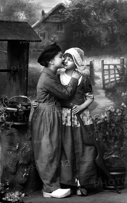 Boy kissing girl, 1920, Two children in old-fashioned clothes in front of a house in the country, Historical photo