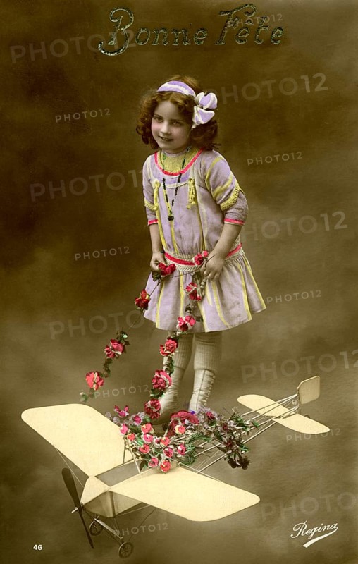 Girl with aeroplane, 1910, Girl in a purple dress posing with a toy aeroplane and flowers, Historical photo