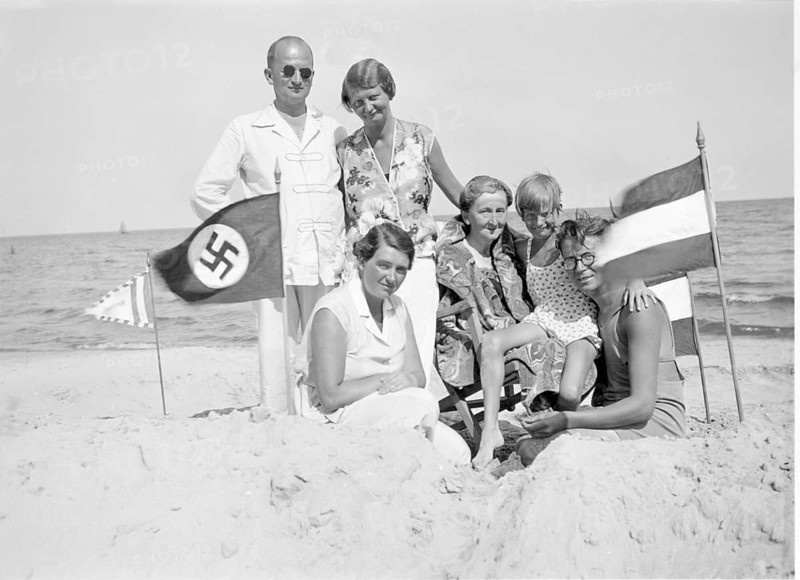 National Socialist family on holiday, Baltic Sea, Beach, 1930s, A family poses on the beach, next to them is a flag with a swastika, Historical photo
