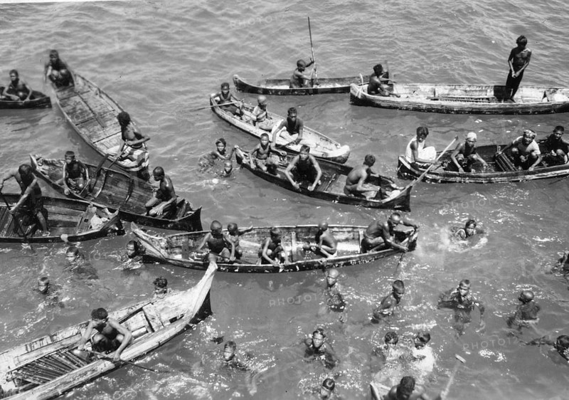 Children in the water between catamarans, Asia 1930s, Group of people in small boats and swimming in the water, Historical photo