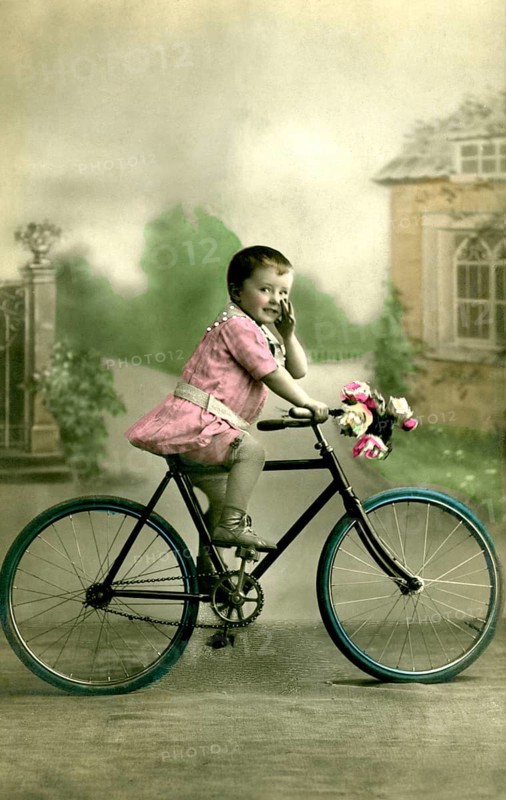 Girl's bicycle, 1910s, Little boy in pink clothes sitting on a bicycle with flower decoration, Historical photo