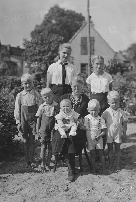 Mother posing with seven children, 1920s, Family portrait of grandmother with grandchildren in the garden in front of a house, summer scene, Historical photo