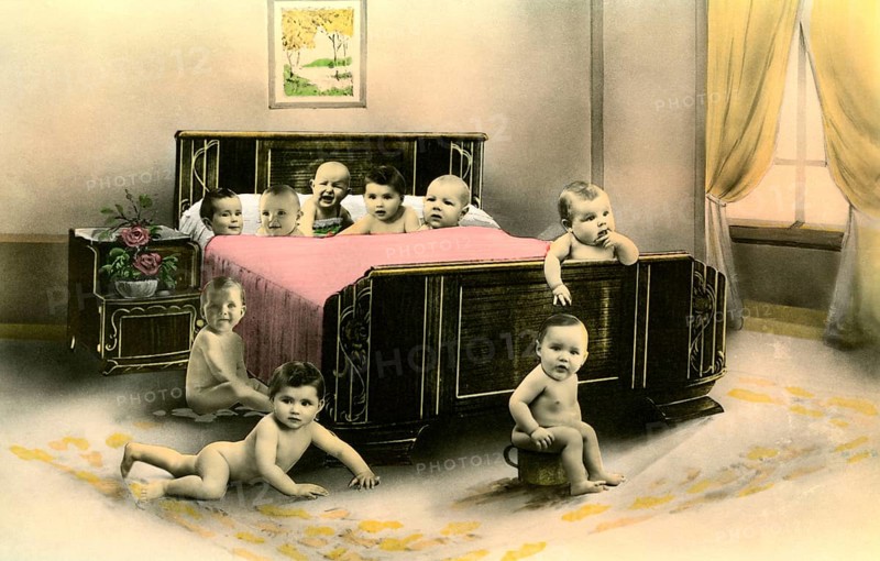 Nine babies in a bed, 1920s, Several babies crawling curiously around a large bed in a room, Historical photo