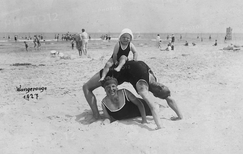 Family on the beach, Wangerooge 1927, An adult lies on the beach while a child sits on his back. The scene radiates joy, historical photo