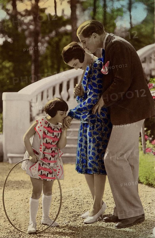 Girl kissing woman's hand, 1920s, child with a ring playing happily, watched by parents in the garden, historical photo