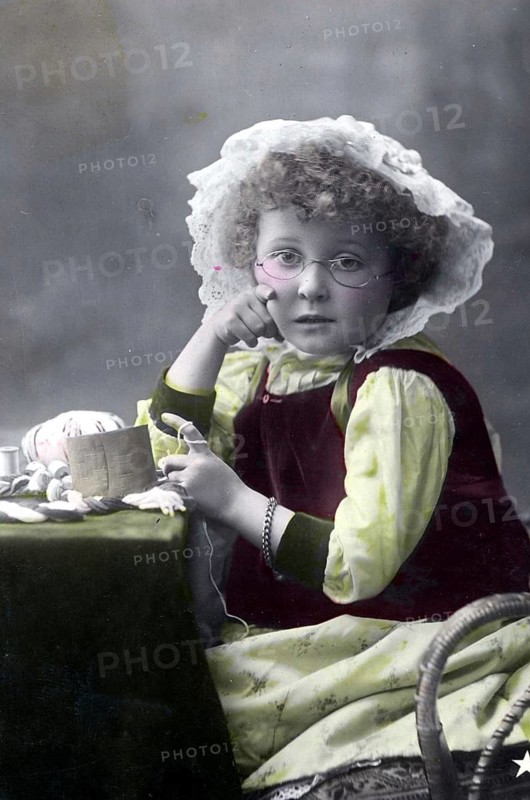 Girl knitting, 1930s, A young girl sits with a crochet set and looks thoughtfully into the camera, Historical photo