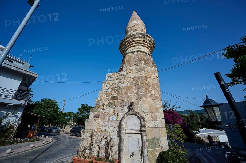 Stone tower and fountain on a street under a blue sky, historical flair, Eski Cami, Minaret, Kos Town, Kos, Dodecanese, Greek Islands, Greece