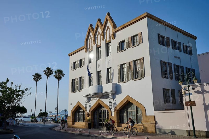 Imposing building in a Mediterranean setting with palm trees and cyclists under a bright blue sky, boutique hotel Albergo Gelsomino, 5-star hotel, Kos Town, Kos, Dodecanese, Greek Islands, Greece