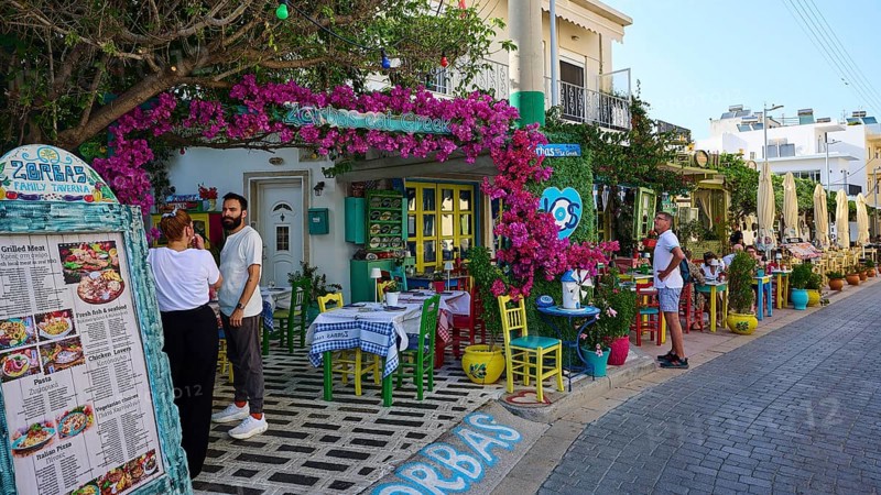 Guests sitting outside in front of a tavern decorated with flowers in kos, friendly atmosphere, Platia Diagora, Kos town, Kos, Dodecanese, Greek islands, Greece