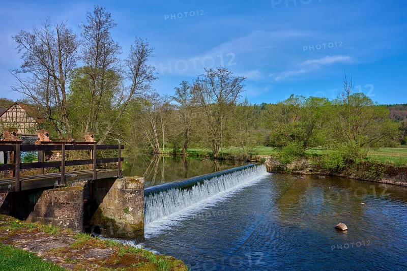 A weir in the river leads to a small waterfall, surrounded by trees, spring, Obersinn, Sinntal, Spessart, Bavaria, Germany