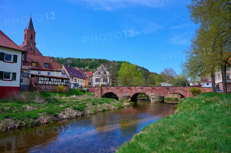 Picturesque small town view with river Saale, bridge and half-timbered houses under blue sky, Gräfendorf, Saale valley, Main Spessart district, Bavaria, Germany