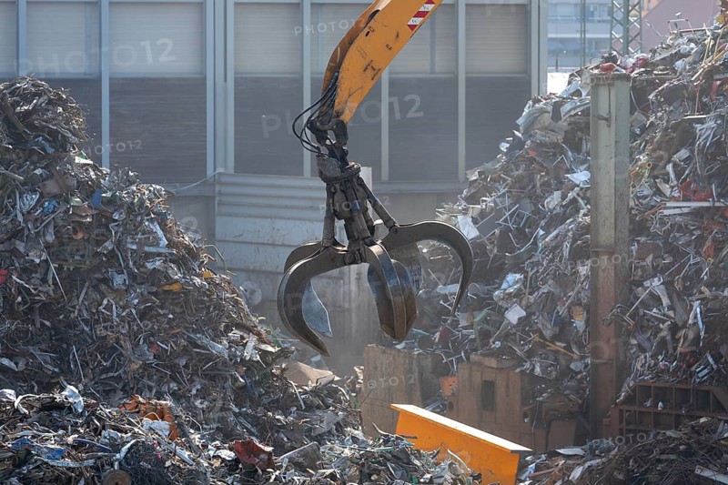 Hydraulic crane lifts scrap metal at the scrap yard