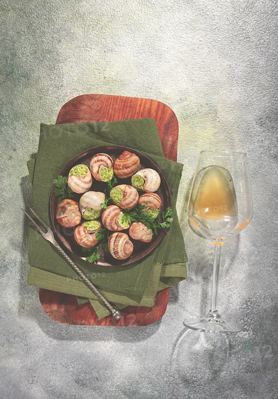 Grape snails stuffed with butter and herbs, top view, glass of wine, French cuisine, no people