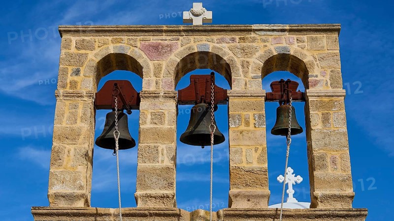 Church of Agios Ioannis Prodromos, Triple bell tower made of stone with blue sky in the background, Skala, harbour, Patmos, Dodecanese, Greek Islands, Greece