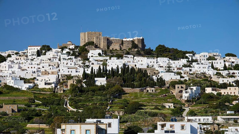 Whitewashed buildings on a green hill with an old castle in the background, Monastery of St John the Theologian, Monastery of St John the Theologian, World Heritage Site 1999, Chora, Patmos, Dodecanese, Greek Islands, Greece