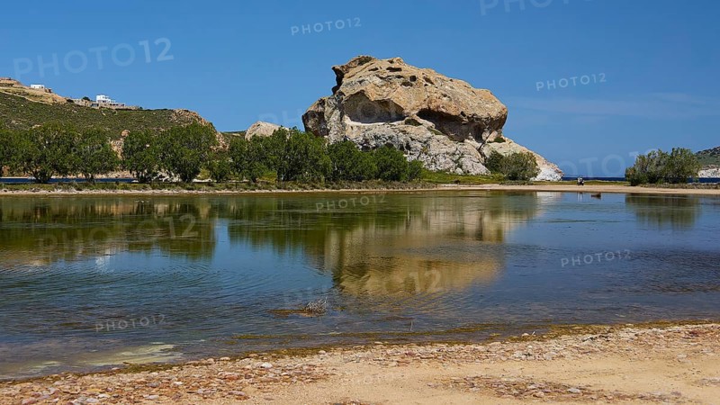 Large rock reflected in a calm lake under a blue sky, Rock of Kalikatsou, Seasonal Salt Lake, Patmos, Dodecanese, Greek Islands, Greece