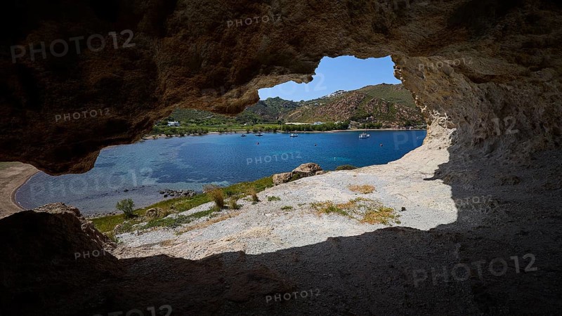 View from a cave onto a blue sea with rocks and coastal landscape in the sunlight, Petra beach, cave, rocks of Kalikatsou, Patmos, Dodecanese, Greek Islands, Greece