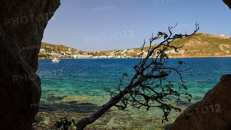 View through a rock opening over the blue sea and the coastal town, Cave, Grikos, Rock of Kalikatsou, Patmos, Dodecanese, Greek Islands, Greece