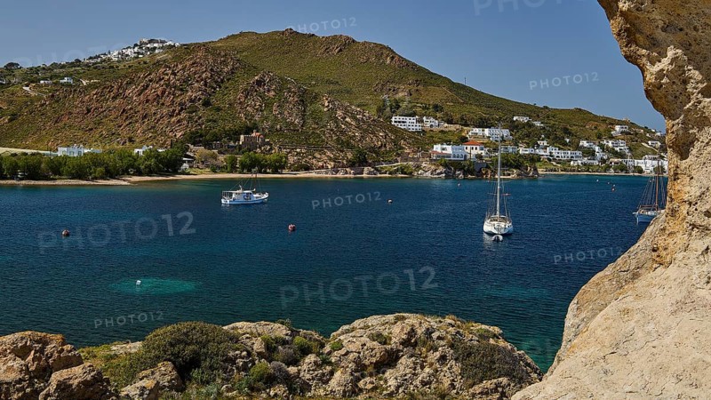 Coast with houses and boats on the calm sea, surrounded by hills and rocks, cave, rocks of Kalikatsou, Patmos, Dodecanese, Greek Islands, Greece