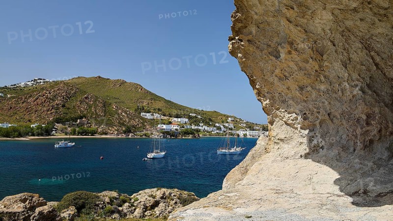 Several sailing boats on the sea, framed by rocks and white coastal town, Grikos, Petra, Chora, rocks of Kalikatsou, Patmos, Dodecanese, Greek Islands, Greece
