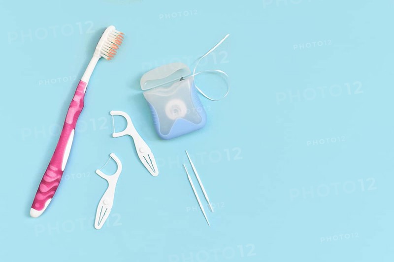 Dental floss, toothpicks and brush on side of blue background with copy space