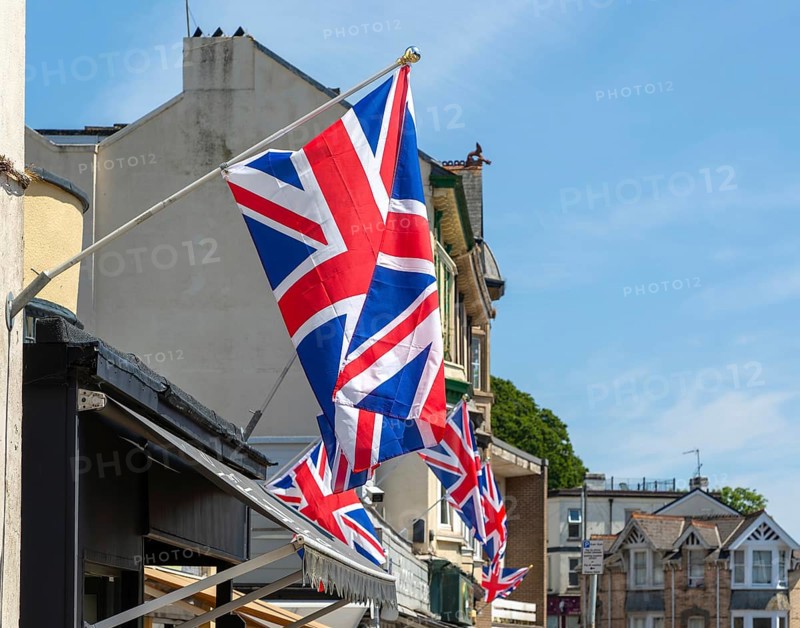 Union Jack flags on shops in street of historic buildings, The Strand, Dawlish, south Devon, England, UK