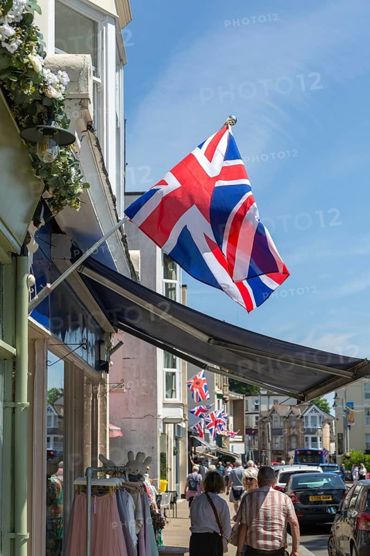 Union Jack flags on shops in street of historic buildings, The Strand, Dawlish, south Devon, England, UK