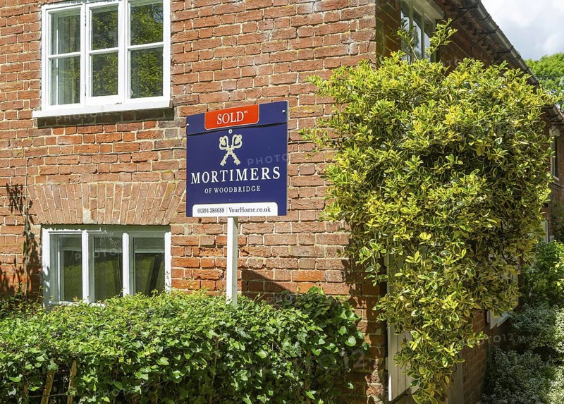 Mortimers estate agent 'Sold' sign outside red brick house, Shottisham, Suffolk, England, UK