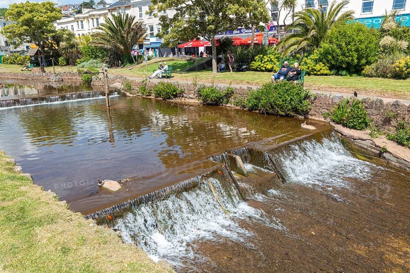 Dawlish Water river flowing through park gardens in town centre, Dawlish, south Devon, England, UK