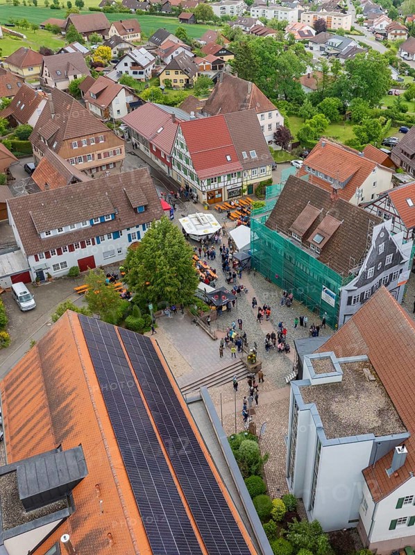 Aerial view of a village square with people and traditional buildings with tiled roofs, family party in Neubulach, district of Calw, Germany