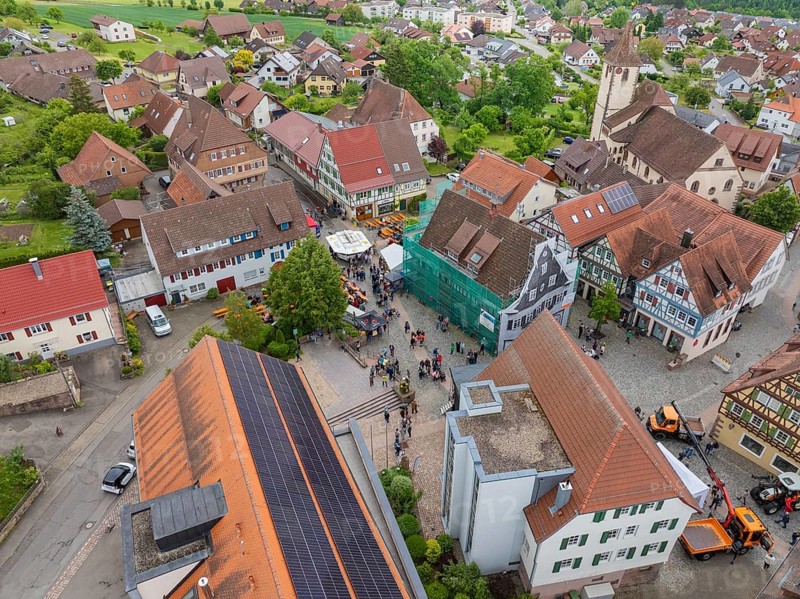 Aerial view of a small village with traditional buildings and a central church with surrounding green areas, family festival in Neubulach, district of Calw, Germany