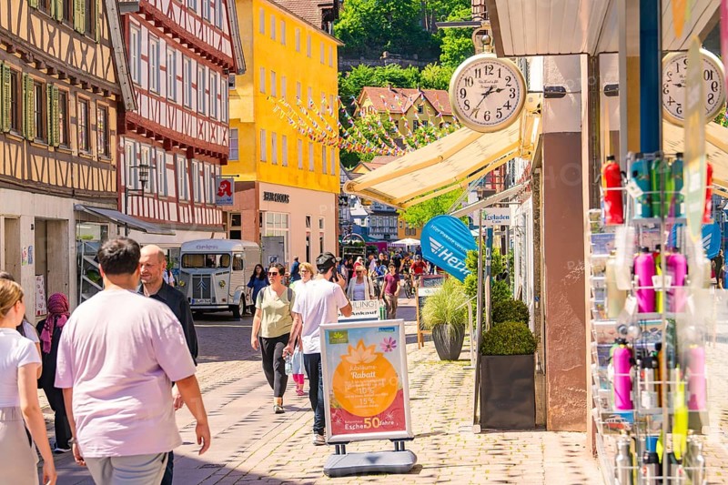 Lively street with half-timbered houses and shops, full of pedestrians on a sunny day, Calw railway station festival, Black Forest, Germany