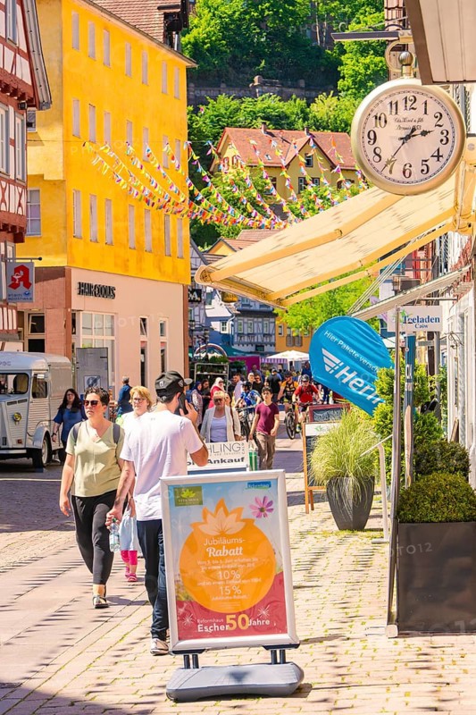 Lively shopping street with cheerful passers-by and colourful decorations on a sunny day, Calw station festival, Black Forest, Germany