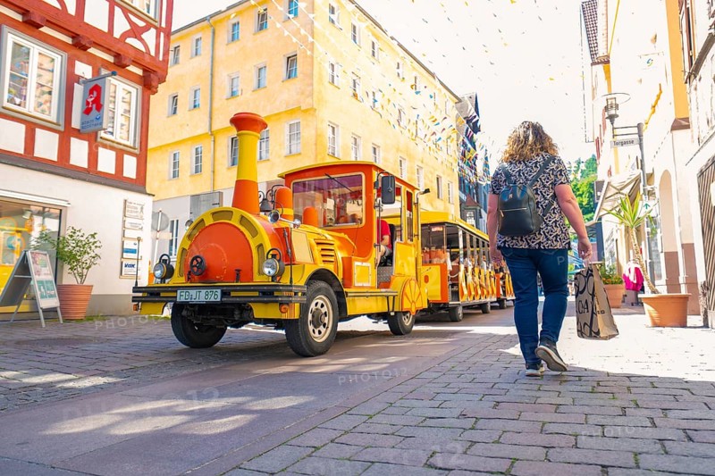 A colourful train runs through a sunny, lively city street, Calw station festival, Black Forest, Germany