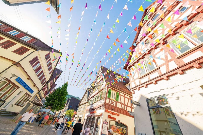 Colourful pennants span a picturesque street with half-timbered houses, Calw station festival, Black Forest, Germany