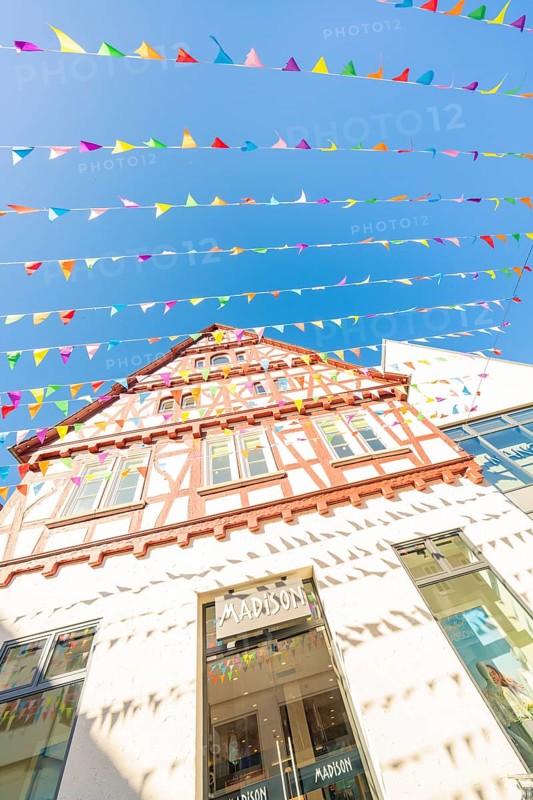 Half-timbered house decorated with colourful pennants under a clear blue sky, Calw station festival, Black Forest, Germany