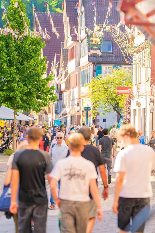 Lively city street with people and sun in summer, Calw railway station festival, Black Forest, Germany